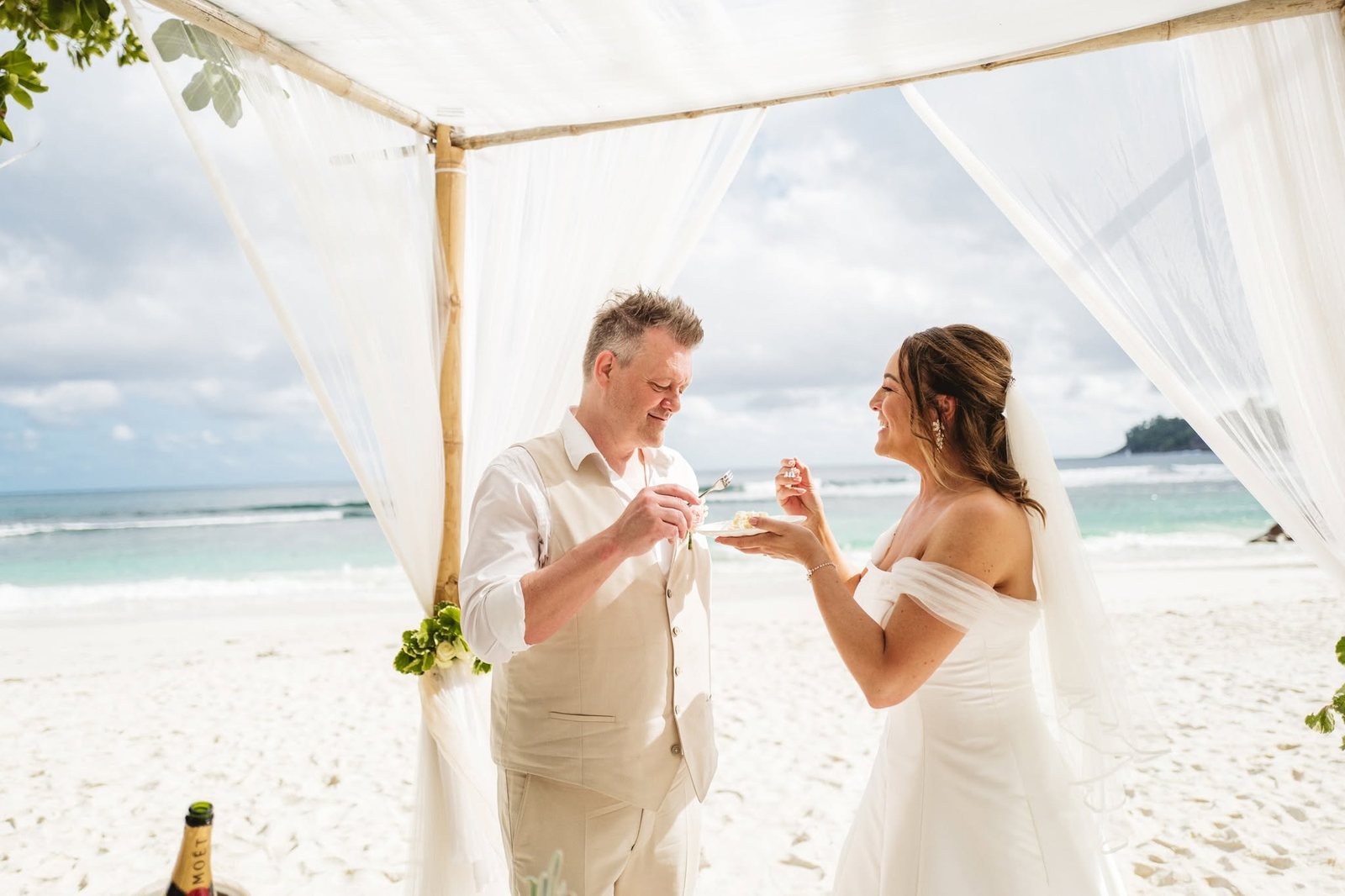 A toast under a draped four post canopy on the beach