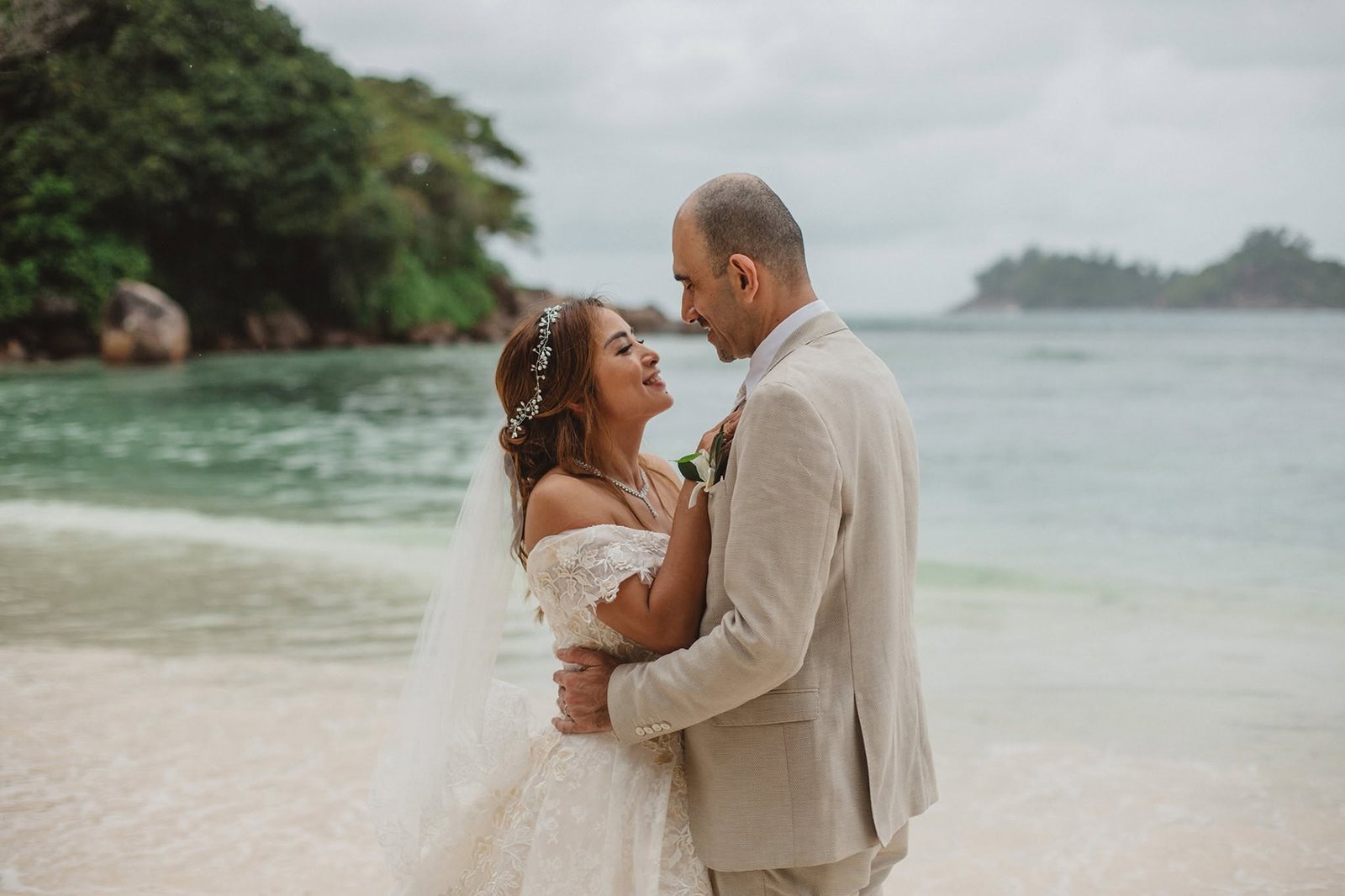 A couple close together on a small beach between granite headlands