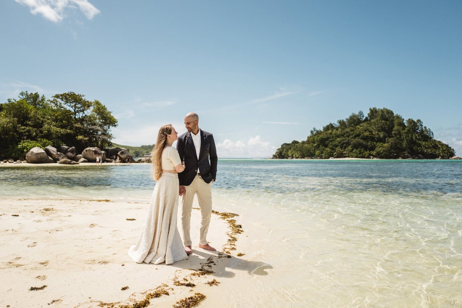The bride and groom on the sand with a wooded islet behind