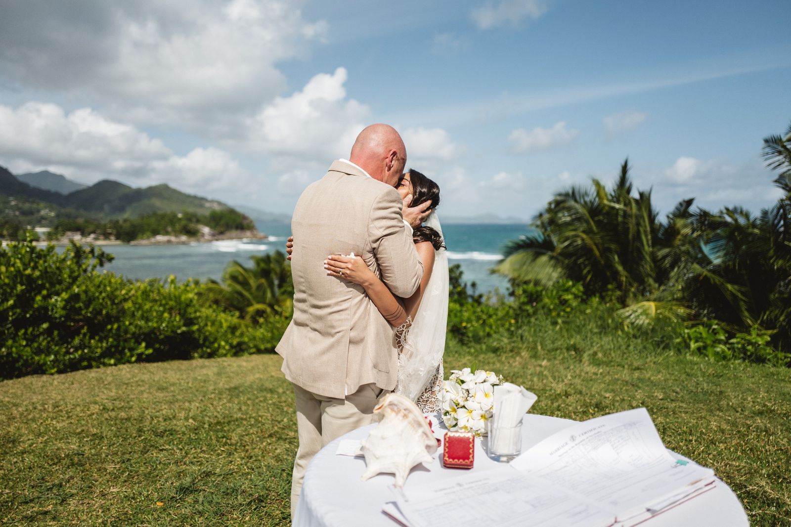 First kiss beside the signing table on the lawn, a conch shell holding the papers