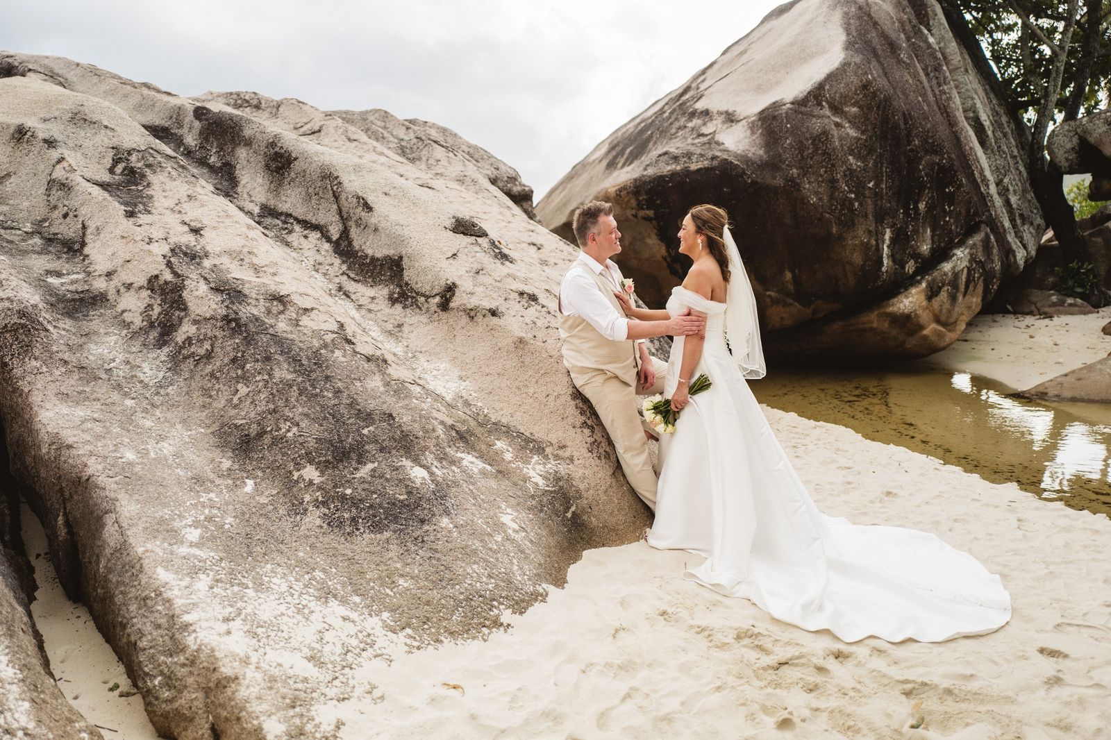 Leaning together against a giant boulder, the long train on the sand