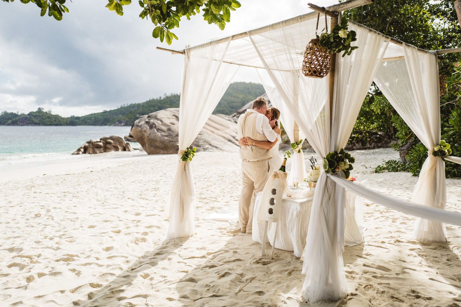 A kiss under the full canopy of a draped beach gazebo
