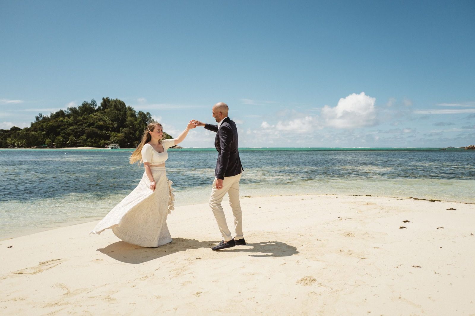 He twirls her barefoot on the sandbar