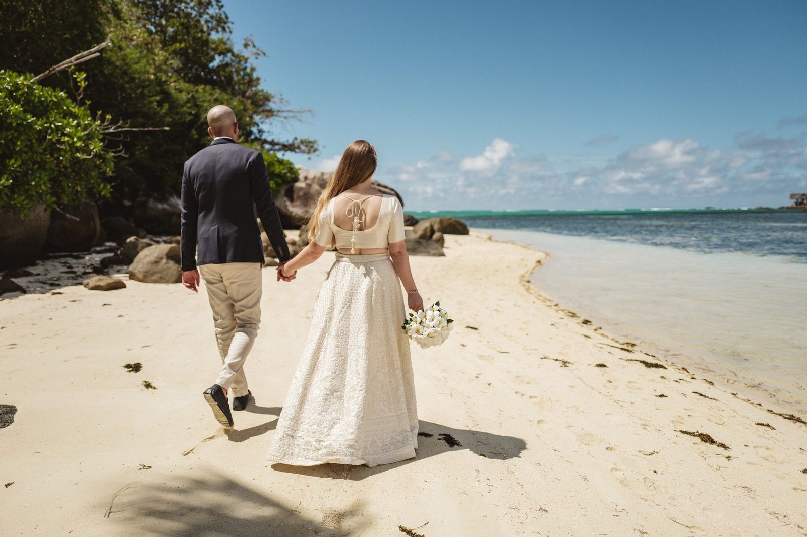 Walking away down the beach hand in hand, bouquet swinging
