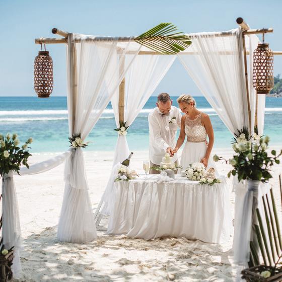 Cutting the cake in a gazebo hung with woven lanterns
