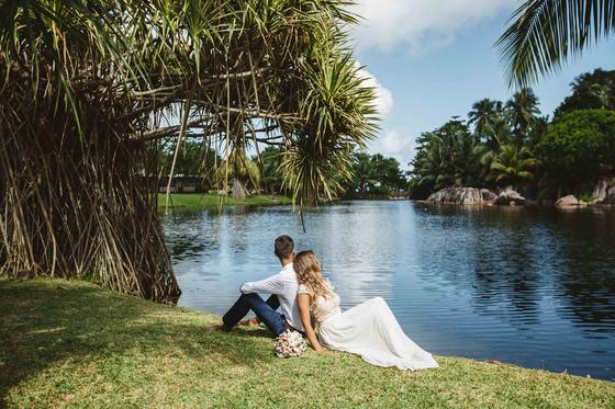 Sitting together on the grass bank of a freshwater lagoon under pandanus