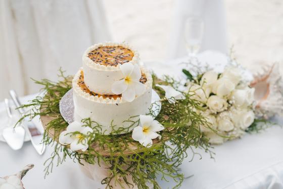 A passion-fruit topped wedding cake dressed with frangipani flowers