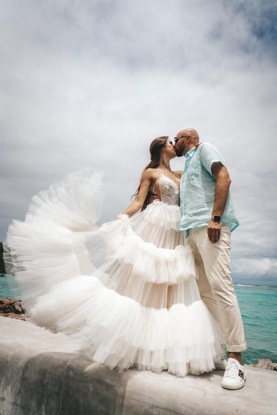 Bride in a layered tulle dress kissing the groom on a granite pier