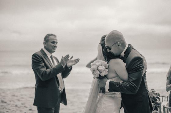 A long embrace after the ceremony while the father applauds, in black and white