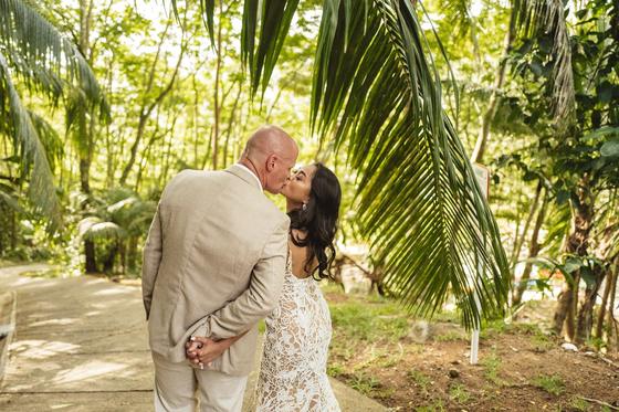 A kiss beneath a low palm frond on a shaded track