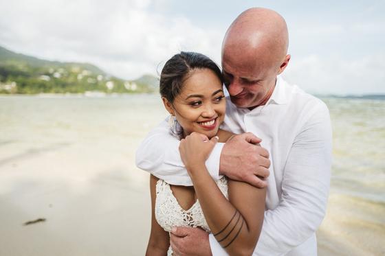 A close embrace and an over-the-shoulder smile on the beach