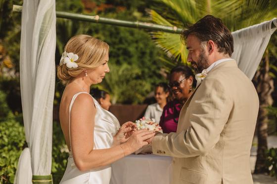 Ring exchange at a golden-lit gazebo with witnesses looking on