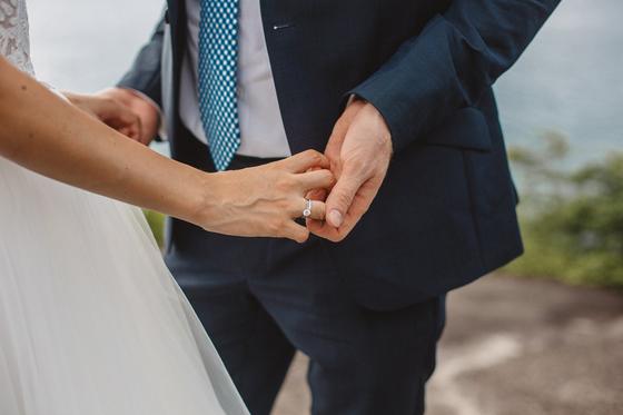 Her hand with the new ring resting in his, navy suit and tulle