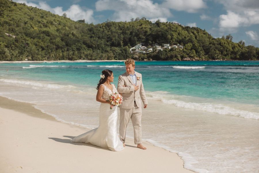 Newlyweds walking the shoreline in Seychelles